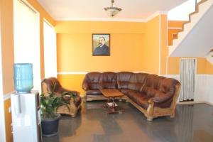 a living room with a brown leather couch at Hotel Kavkasioni in Kvareli
