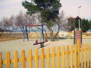 un parque con parque infantil con valla y columpio en Room for 2 by the sea en Betina