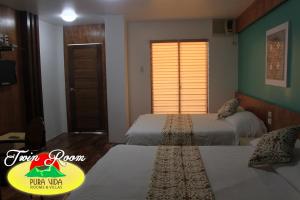 a hotel room with two beds and a window at Pura Vida Resort in Tagaytay