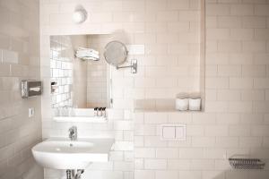 a white bathroom with a sink and a mirror at Hotel The Exchange in Amsterdam