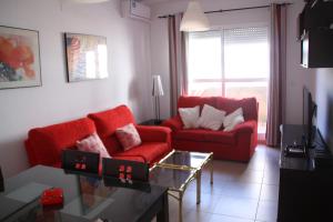 sala de estar con sofá rojo y mesa en Ático dúplex 2 linea de playa en La Antilla, en La Antilla