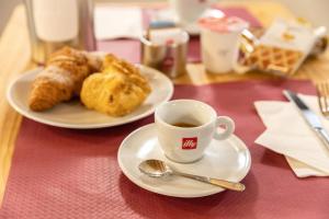 a table with two plates of pastries and a cup of coffee at Hotel All'Arco in Trieste