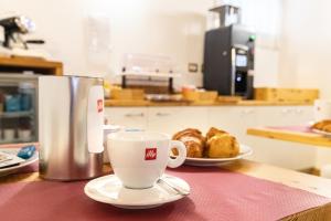a table with a coffee cup and a plate of pastries at Hotel All'Arco in Trieste