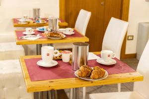 a table with croissants and coffee cups on it at Hotel All'Arco in Trieste