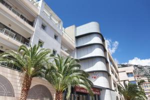 a building with palm trees in front of it at Odalys City Beausoleil les Hauts de la Principauté in Beausoleil