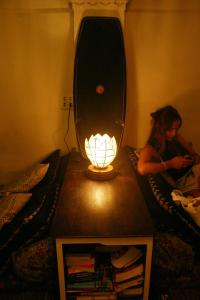 a woman laying in bed with a lamp on a table at Born Free Hostel in Bangkok
