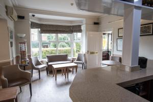 a living room with chairs and a table and windows at The Corner House Hotel in Horley