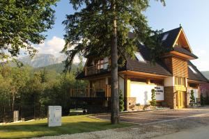 una casa con un árbol delante en Rezydencja Sobiczkowa Apartamenty, en Zakopane