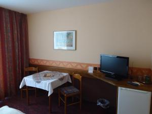 Zimmer mit einem Schreibtisch, einem TV und einem Tisch in der Unterkunft enjoyHotel garni Korntal Stuttgart in Stuttgart