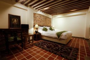 1 dormitorio con cama y pared de ladrillo en Heranya Yala en Katmandú