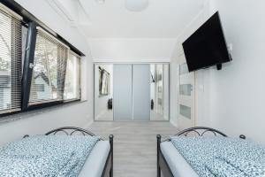 two beds in a room with a flat screen tv at Ekskluzywny wypoczynek w domu nad morzem in Pobierowo