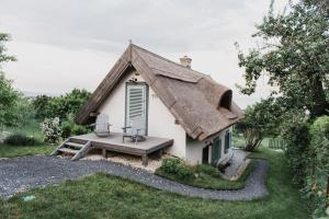 uma pequena casa com um telhado de palha e um banco em Noemi's Cottage em Balatongyörök