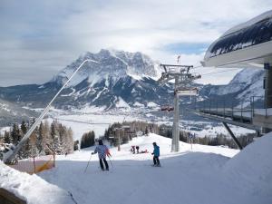 eine Gruppe von Menschen fährt mit Skiern einen schneebedeckten Berg hinunter in der Unterkunft Haus Gipfelblick in Lermoos