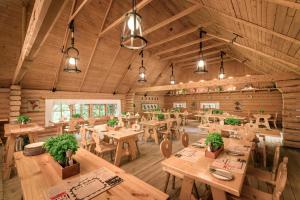 un restaurante con mesas de madera, sillas y luces en Hotel Warszawianka, en Jachranka