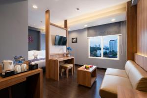 une chambre d'hôtel avec un canapé, un lit et une fenêtre dans l'établissement BATIQA Hotel Darmo - Surabaya, à Surabaya