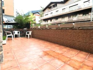 a patio with two chairs and a brick wall at Poblat Andorrá, Encamp, con terraza, zona Grandvalira in Encamp