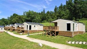 a row of lodges in a field with grass and trees at Camping White Rock in Castellane