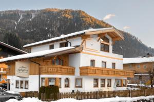 a white house with wooden balconies in front of a mountain at Landhaus Brigitte in Flachau