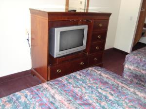 una TV seduta su un comò accanto a un letto di Willow Springs Motel a Cheney