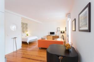 a living room with an orange couch and a bedroom at Bairrus Lisbon Apartments - Rossio in Lisbon
