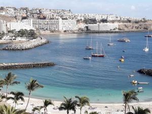 a beach with palm trees and boats in the water at ESTRELLA DEL MAR Amazing Loft Casa Cosy in La Playa de Arguineguín