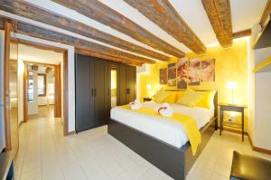 um quarto com uma grande cama branca com almofadas amarelas em Calle dei Fabbri San Marco Apartment em Veneza