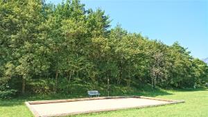 a bench sitting in a field next to trees at Camping White Rock in Castellane