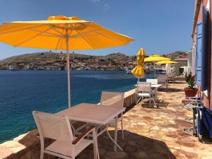 a table and chairs with an umbrella and the water at Villa Hiona in Halki