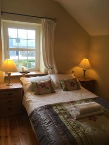 a bedroom with a bed with two lamps and a window at Restored School Master’s House in Valentia Island