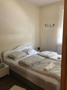 a bedroom with a bed with white sheets and pillows at Candy Apartman in Keszthely