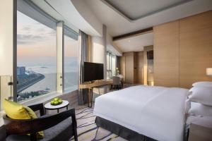 um quarto com uma grande cama branca e uma grande janela em Fliport Wutong Hotel-Free Welcome Fruit & Near Exhibition Center em Xiamen