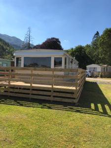 a trailer in a field with a fence at 57 Glenfinart Caravan Park in Ardentinny +4 photos