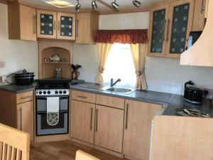 a kitchen with a stove and a sink at 57 Glenfinart Caravan Park in Ardentinny