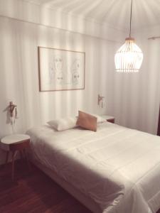 Un dormitorio con una gran cama blanca y una lámpara de araña. en Gare Do Sol, en Aveiro