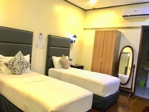 een hotelkamer met 2 bedden en een spiegel bij The Ambassador Hotel in Tacloban