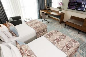 a hotel room with two beds and a desk at Dedeman Cizre Hotel in Jesıret ibn Omar