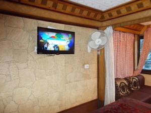 a room with a tv on a stone wall at Comfortable Rooms Fitted With Modern Amenities in Nainital