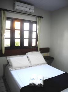 Schlafzimmer mit einem Bett mit weißer Bettwäsche und einem Fenster in der Unterkunft Praia Apart Hotel in Natal