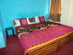a bedroom with a large wooden bed with purple sheets at Hotel Raj Mahal(100 metres from Mall road) in Nainital
