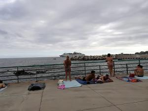 a group of people sitting on the sidewalk near the water at Casa Zona Velha - Caetano in Funchal