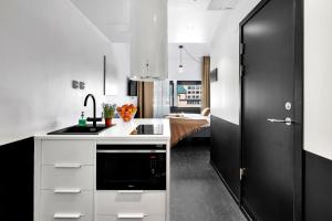 a kitchen with white cabinets and a black door at Forenom Aparthotel Oslo in Oslo