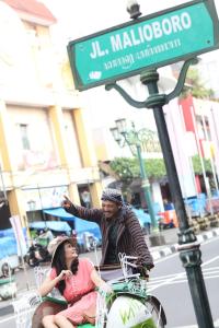 a man and a woman riding on the back of a cart at Whiz Hotel Malioboro Yogyakarta in Yogyakarta