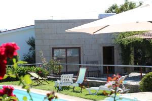 a house with a swimming pool and a white umbrella at Casa Paz do Outeiro in Paredes de Coura