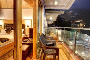 a room with a balcony with a bedroom and a bed at Hill County Resort & Spa in Manāli