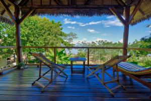 a porch with two chairs and a table on it at Coco Komba Lodge in Nosy Komba