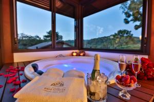 uma banheira de hidromassagem com uma garrafa de vinho e copos em Chalés Cinco Estrelas em Monte Verde