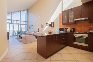 uma cozinha com armários castanhos e uma sala de estar em Seaside Village B24 by CTHA em Bloubergstrand
