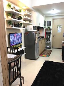 een keuken met een koelkast en een tafel en een televisie bij SMDC Field Residences - SM Sucat in Manilla