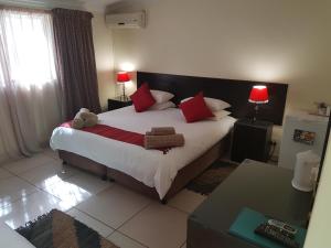 a bedroom with a large bed with red pillows at 360 Eastwoods Guesthouse in Pretoria