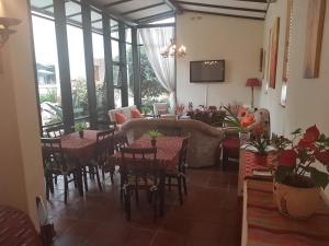 360 Eastwoods Guesthouse في بريتوريا: غرفة طعام مع طاولات وكراسي ونوافذ